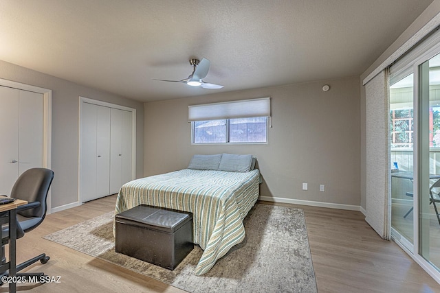 bedroom featuring access to exterior, wood-type flooring, two closets, and ceiling fan