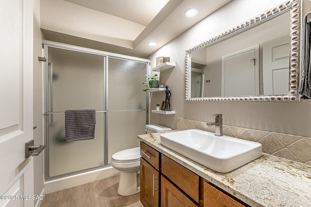 bathroom featuring tasteful backsplash, vanity, hardwood / wood-style flooring, toilet, and a shower with shower door