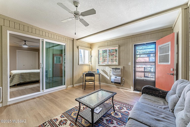 living room with ceiling fan, light hardwood / wood-style floors, and a textured ceiling