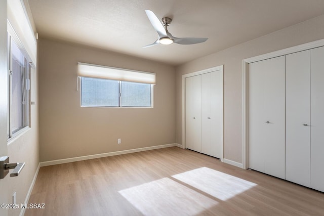 unfurnished bedroom with ceiling fan, light hardwood / wood-style floors, and two closets