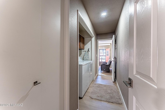 corridor with washer and clothes dryer, a textured ceiling, and light wood-type flooring