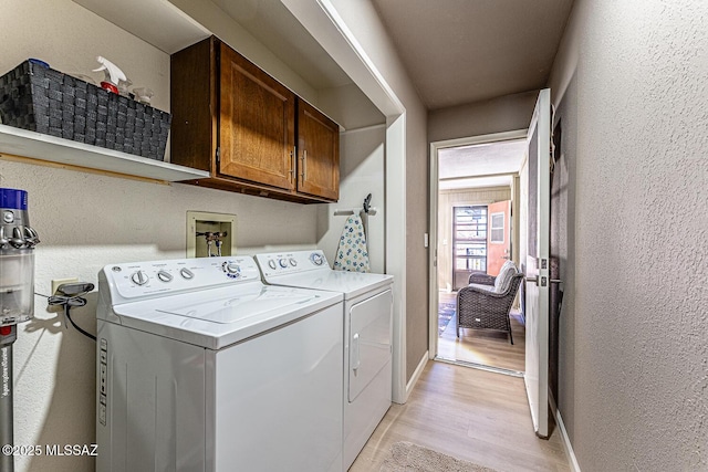 clothes washing area featuring light hardwood / wood-style floors, cabinets, and separate washer and dryer