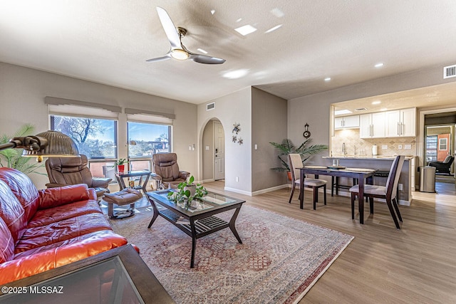 living room featuring a textured ceiling, light hardwood / wood-style flooring, and ceiling fan