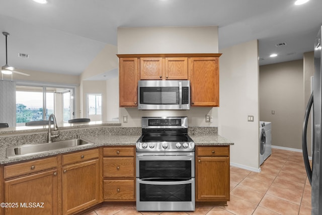 kitchen featuring sink, light tile patterned floors, washer / dryer, and appliances with stainless steel finishes