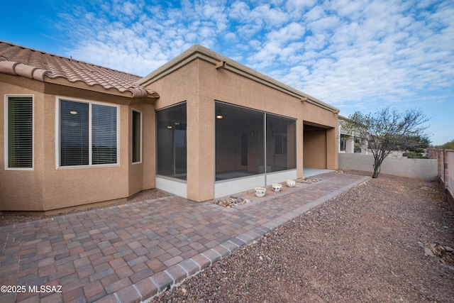 rear view of property featuring a sunroom and a patio area