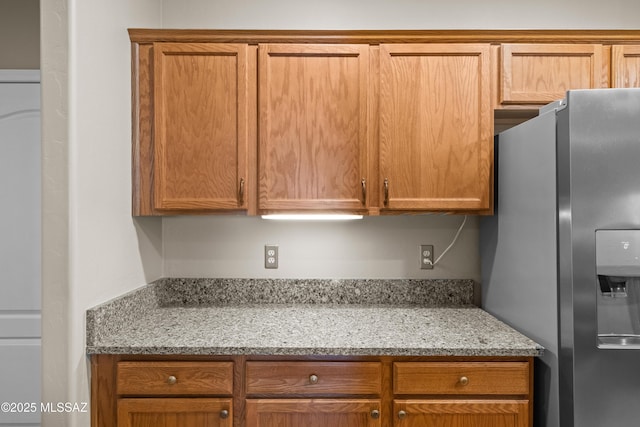 kitchen featuring stainless steel fridge with ice dispenser and light stone countertops