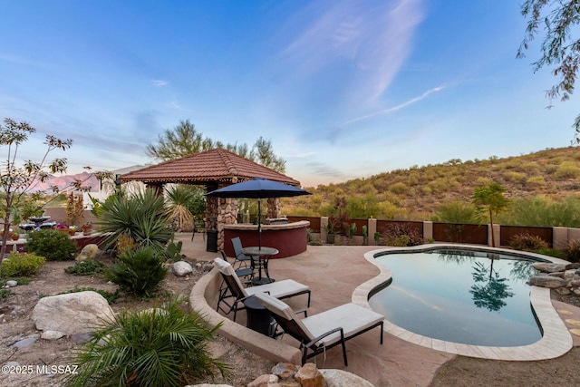 view of pool with fence, outdoor dry bar, a gazebo, a fenced in pool, and a patio area