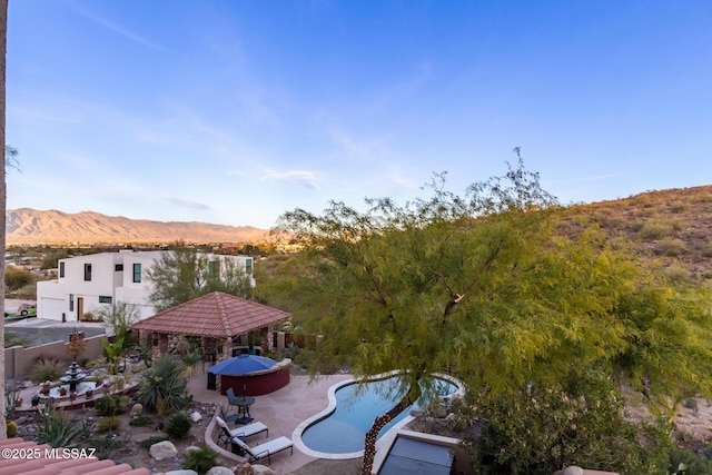 exterior space with an outdoor pool, a patio area, a mountain view, and fence