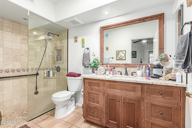 bathroom featuring toilet, vanity, tile patterned floors, and tiled shower