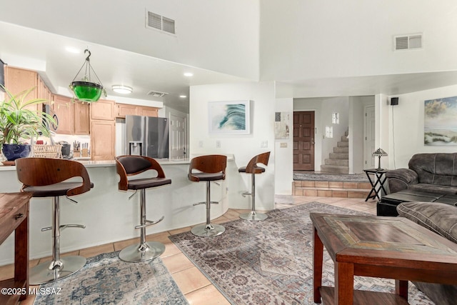 living area with stairs, a high ceiling, light tile patterned flooring, and visible vents