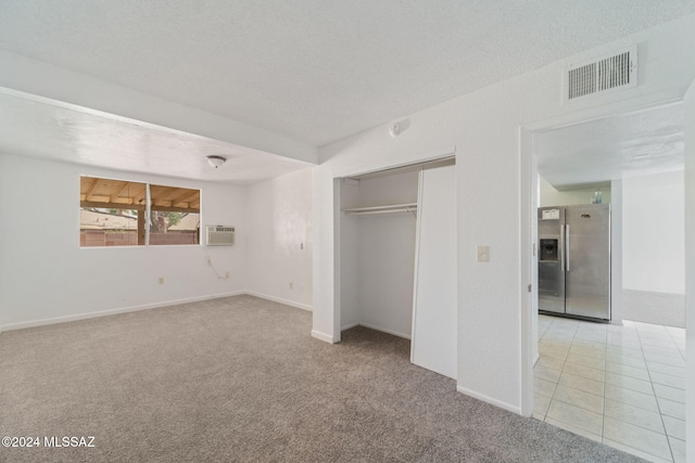 unfurnished bedroom with stainless steel fridge with ice dispenser, a closet, light colored carpet, and a textured ceiling