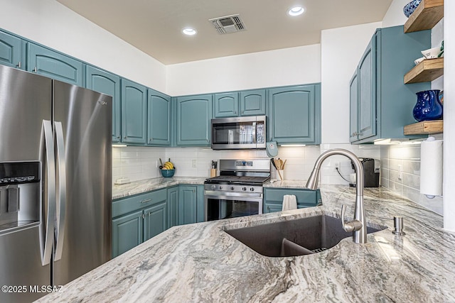 kitchen featuring blue cabinetry, sink, stainless steel appliances, tasteful backsplash, and light stone counters