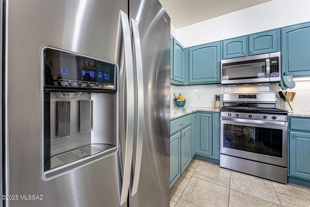 kitchen featuring backsplash, light stone countertops, blue cabinetry, and appliances with stainless steel finishes