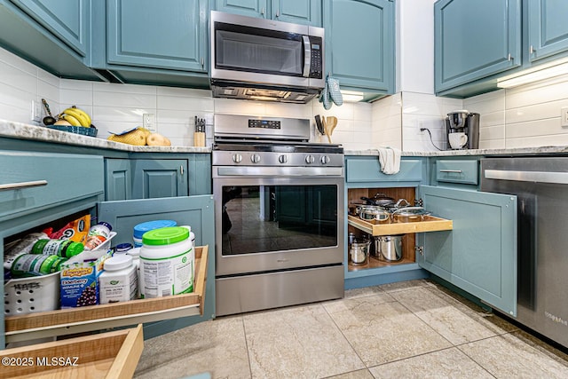 kitchen featuring blue cabinetry, decorative backsplash, light tile patterned flooring, and stainless steel appliances