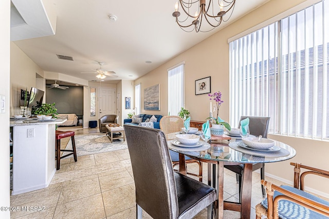 dining area with ceiling fan with notable chandelier and light tile patterned floors