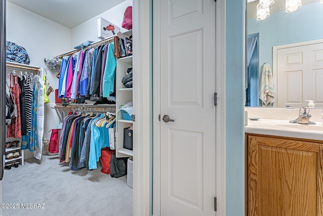 walk in closet featuring light colored carpet and sink