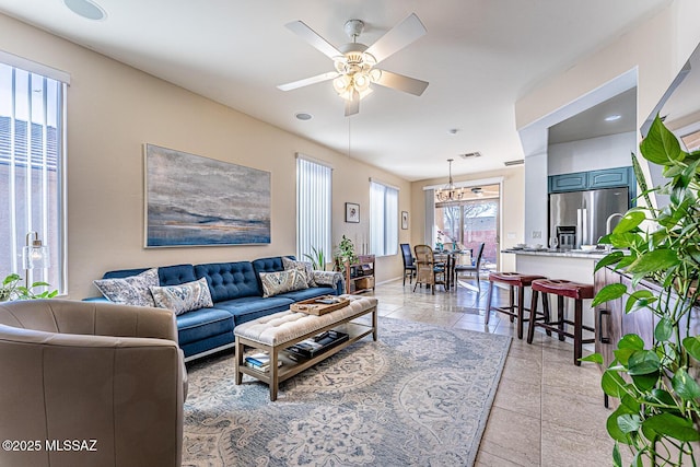 living room with ceiling fan with notable chandelier