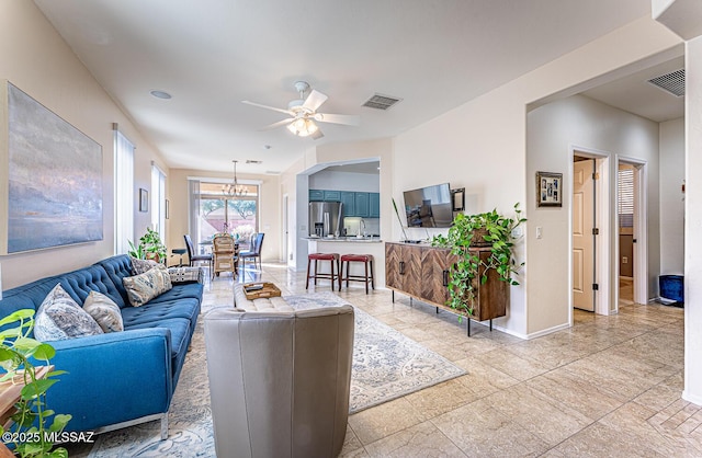 living room with ceiling fan with notable chandelier