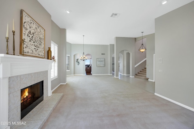 unfurnished living room featuring light colored carpet, a notable chandelier, and a fireplace