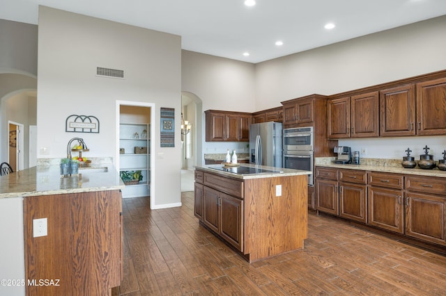 kitchen with appliances with stainless steel finishes, sink, a high ceiling, and an island with sink