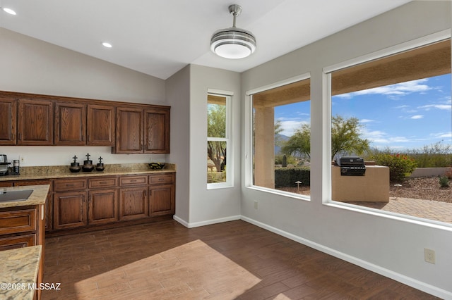 kitchen with light stone countertops, vaulted ceiling, and dark hardwood / wood-style flooring