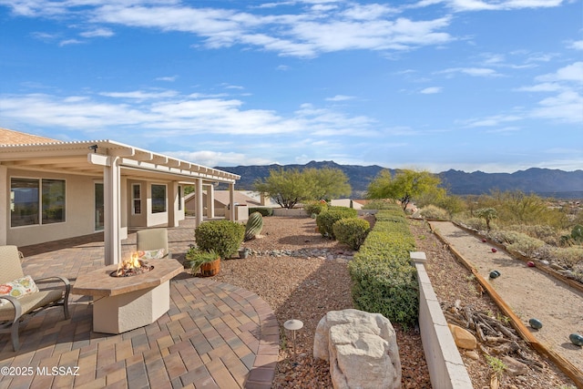 view of patio with a mountain view and a fire pit