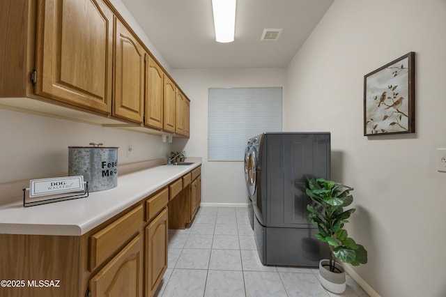 clothes washing area with independent washer and dryer, light tile patterned flooring, sink, and cabinets