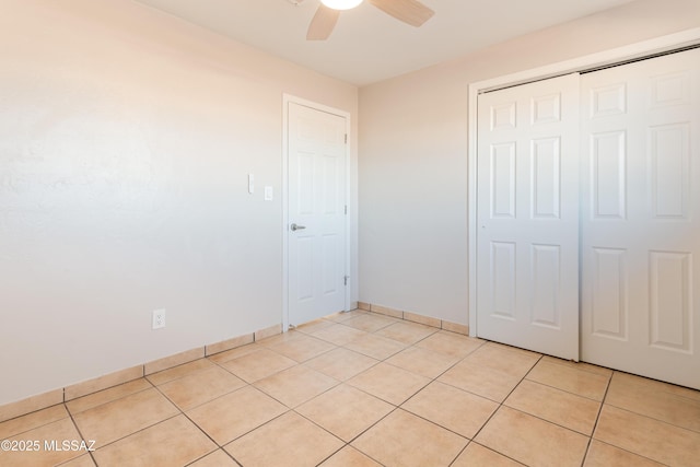 unfurnished bedroom with light tile patterned floors, ceiling fan, and a closet