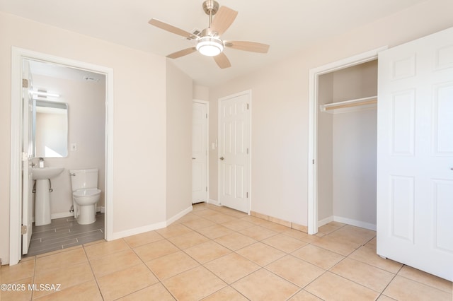 unfurnished bedroom featuring connected bathroom, light tile patterned floors, ceiling fan, and a closet