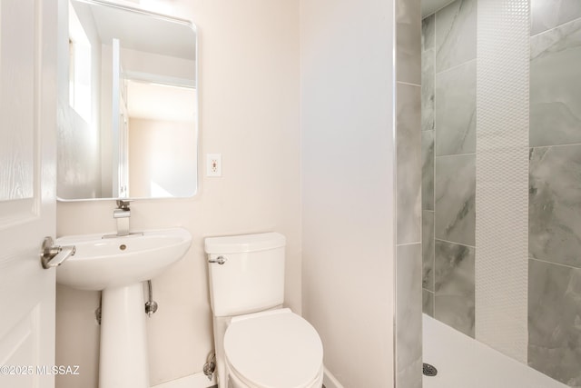 bathroom featuring tiled shower and toilet