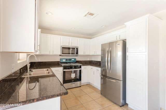 kitchen with stainless steel appliances, white cabinetry, sink, and light tile patterned floors