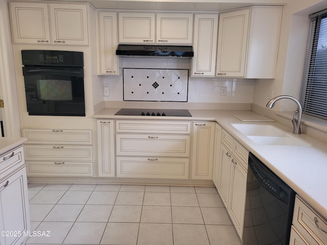 kitchen featuring sink, light tile patterned flooring, black appliances, and cream cabinetry