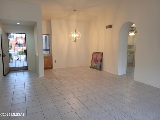 tiled spare room with ceiling fan with notable chandelier