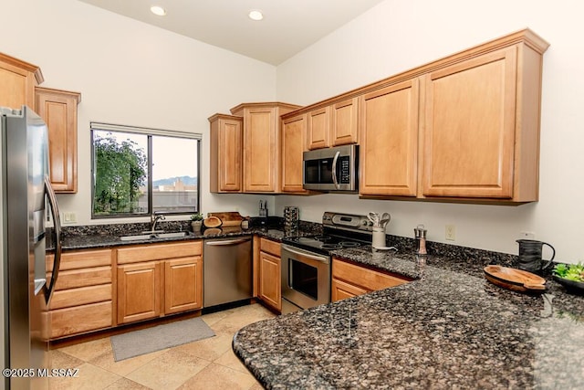 kitchen with sink, light tile patterned flooring, dark stone countertops, and stainless steel appliances