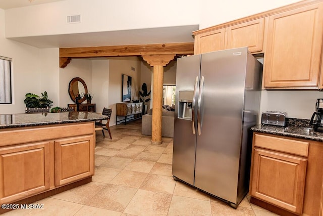 kitchen featuring stainless steel refrigerator with ice dispenser, ornate columns, and dark stone countertops