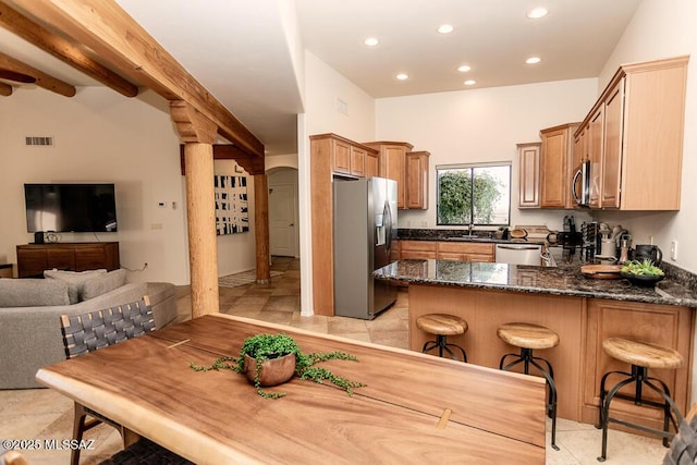 kitchen with beam ceiling, a kitchen breakfast bar, kitchen peninsula, and stainless steel appliances