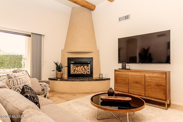 living room featuring a towering ceiling, beam ceiling, and a fireplace