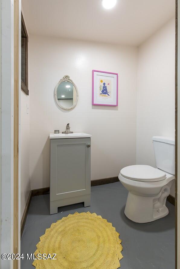 bathroom with vanity, toilet, and concrete floors