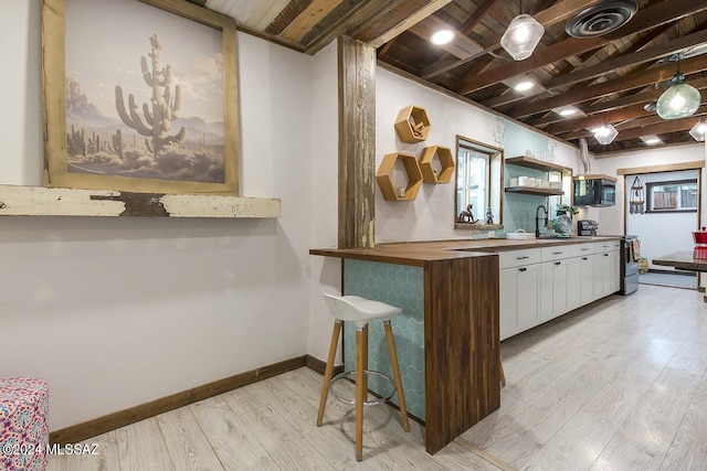 kitchen with hanging light fixtures, kitchen peninsula, electric stove, white cabinets, and light wood-type flooring