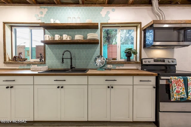 kitchen featuring backsplash, stainless steel appliances, sink, butcher block countertops, and white cabinetry