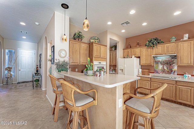 kitchen featuring hanging light fixtures, white appliances, a breakfast bar area, and light tile patterned floors