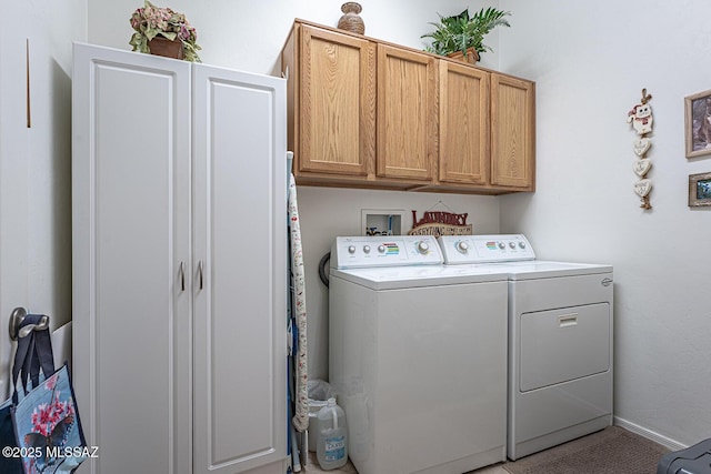 clothes washing area with washer and clothes dryer and cabinets