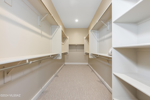 walk in closet with light carpet