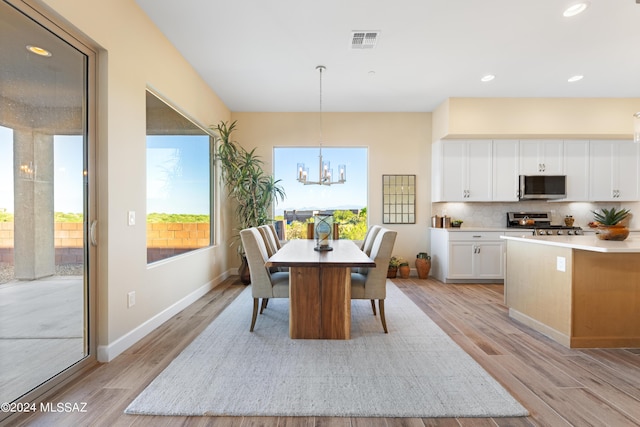 dining space with light hardwood / wood-style floors and an inviting chandelier