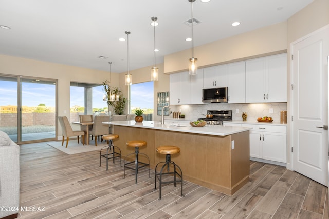 kitchen with white cabinets, appliances with stainless steel finishes, pendant lighting, and a large island