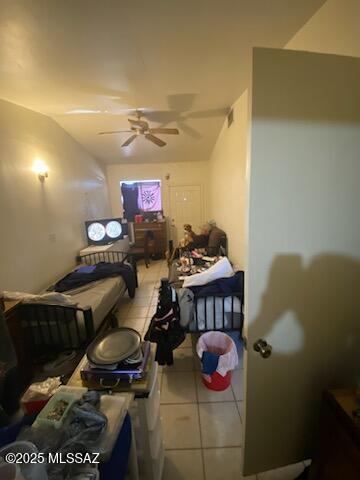 bedroom featuring ceiling fan, light tile patterned flooring, and lofted ceiling