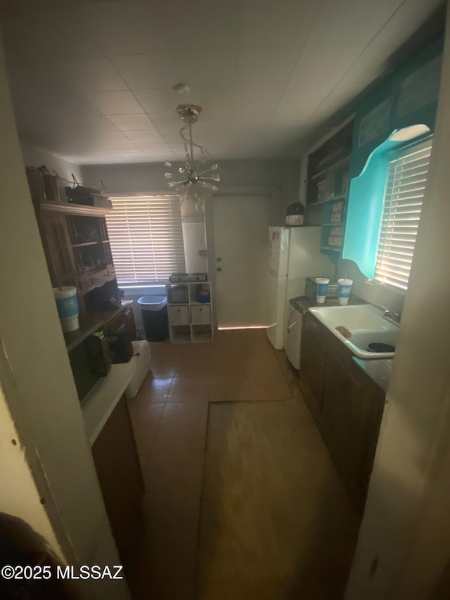 kitchen with white refrigerator, sink, and a chandelier