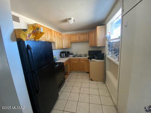 kitchen featuring black appliances, light tile patterned floors, sink, and light brown cabinetry