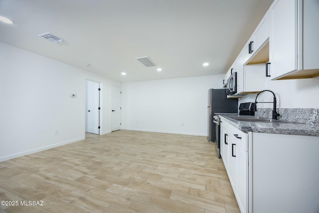 kitchen featuring white cabinets, light wood-type flooring, sink, and dark stone countertops