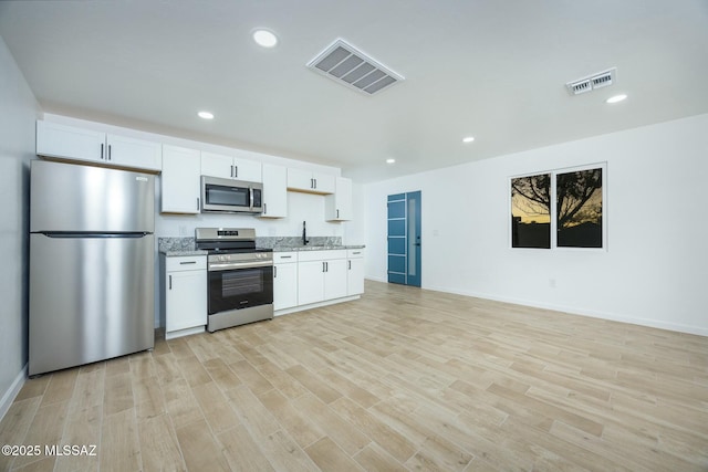 kitchen featuring light stone counters, stainless steel appliances, sink, light hardwood / wood-style flooring, and white cabinets